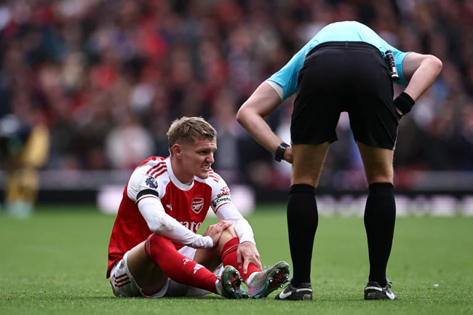 Arsenal's Norwegian midfielder Martin Odegaard (L) reacts after picking up an injury during the English Premier League football match between Arsenal and West Ham United at the Emirates Stadium in London on October 4, 2025.