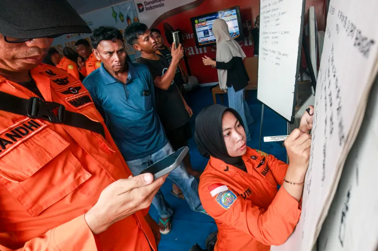 Relatives of passengers of the Virgo Transport 8 ferry wait for updates as a search-and-rescue agency officer writes on a whiteboard in Banjarmasin, South Kalimantan, Indonesia, September 13, 2026 [INFUZ via AFP]